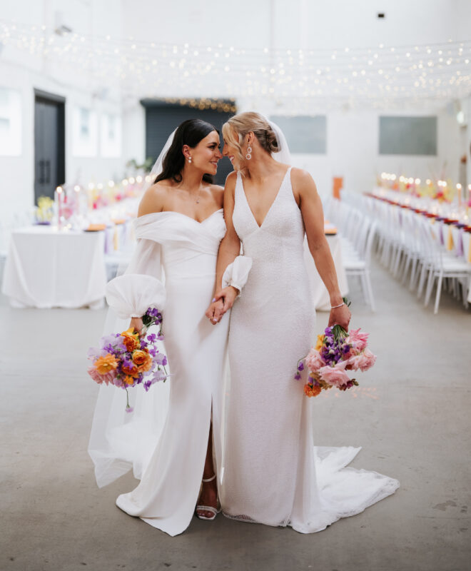 A happy couple shares a special moment in the reception hall at The Wool Mill, holding beautiful bouquets by Anatomy of Flowers, creating a romantic and memorable atmosphere for their celebration.