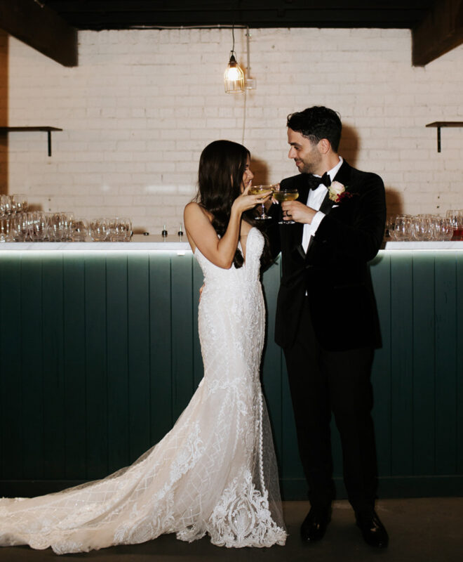 The happy couple shares a drink in the speakeasy bar at The Wool Mill, a premier Melbourne wedding venue, celebrating their special day in this unique, stylish setting.