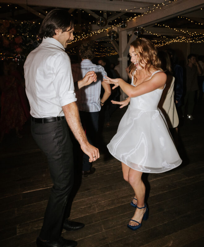Happy couple dancing on the reception floor at Gather and Tailor, a luxury Melbourne wedding venue, under a canopy of twinkling fairy lights. The romantic and sophisticated atmosphere enhances this unforgettable wedding celebration.
