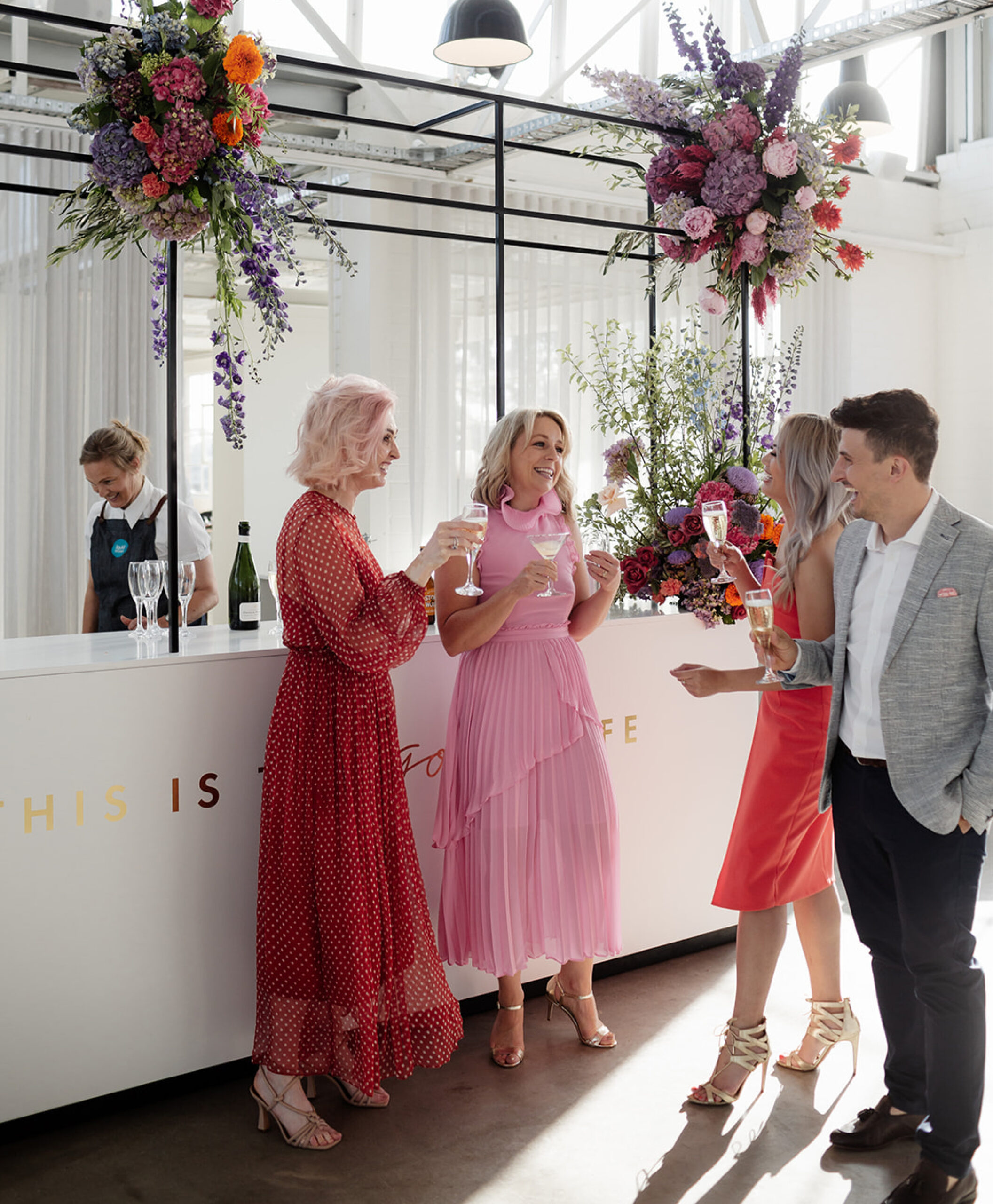Lively moments at The Button Factory as guests sip drinks at a beautifully styled bar, enhanced with vibrant florals by Anatomy of Flowers, creating a dynamic and stylish atmosphere at this unique Melbourne venue.