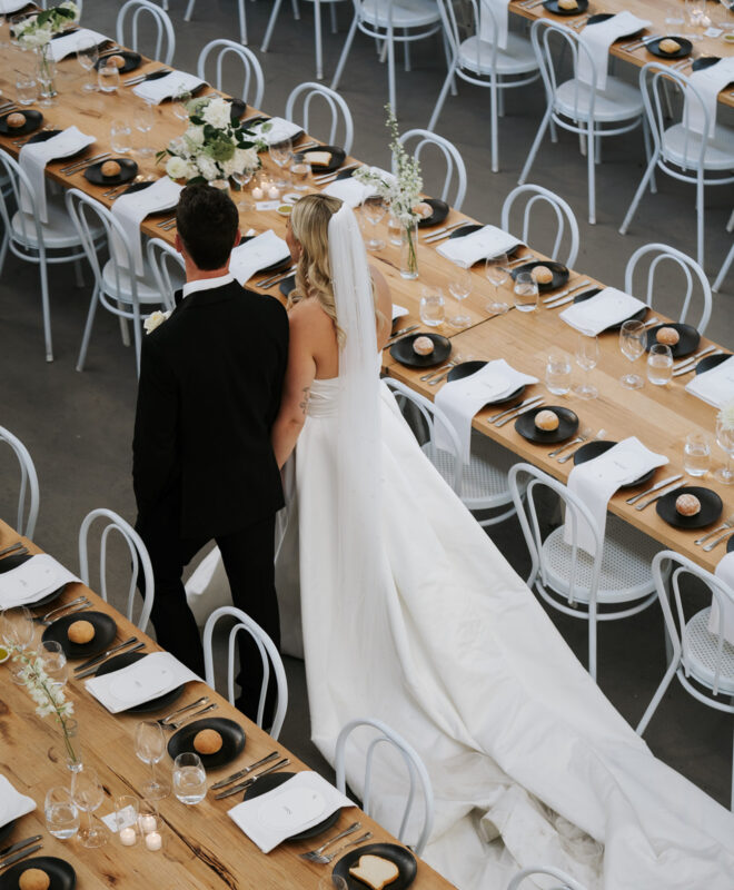 A stunning bride and groom admire their beautifully styled reception space at The Wool Mill, a modern industrial-chic wedding venue in Melbourne.