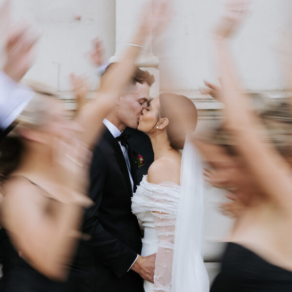 A breathtaking moment, artistically captured by Art of Grace, as the couple kisses in celebration, surrounded by a blur of joyful guests.