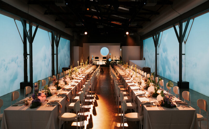 Immersive Corporate Event with long styled tables and wall projections.