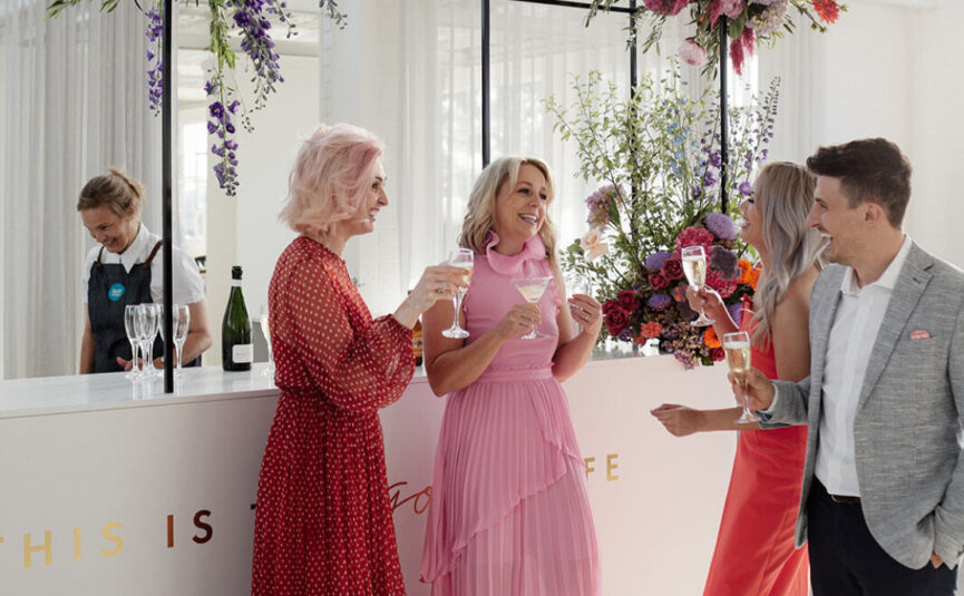 End-of-financial-year party at The Button Factory, a vibrant Nudo venue in Melbourne, with guests celebrating by the bar, adorned with florals by Anatomy of Flowers.